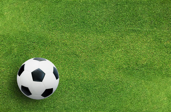 Soccer football ball on green grass of soccer field background.