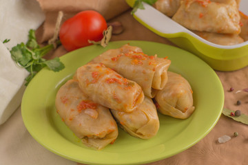 Cabbage leaf with filling, tomato sauce on green plate close up. European food. 