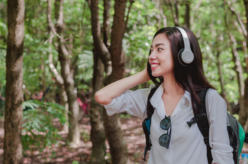 attractive woman adventure hiker go to trekking in the forest sightseeing natural at holiday travel concept with headphone listening music.