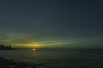 Sunset over Malecon and Atlantic Ocean with residential building in background - Havana, Cuba 