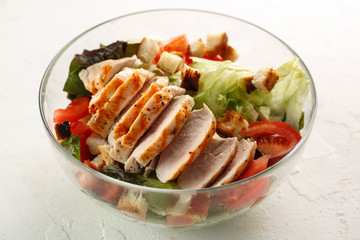 salad cesar with chicken grill in glass bowl on white table. Top view. Flat lay.