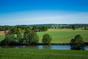 Obraz premium Green field, river and blue sky