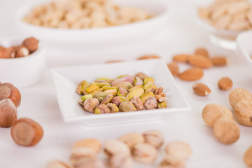 healthy snack selection of various nuts  on white wood background