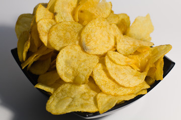 Crispy potato chips, in a plate, on a white background. Close-up.