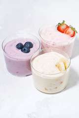sweet yoghurts with fruits and berries on white background, vertical top view