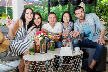 young people cafe talk communicate summer drinks cocktail together group happy smile girl boy man woman green leaves white