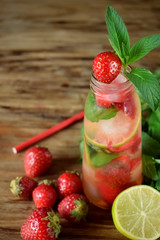 Lemonade with strawberry, lime, ice cubes and mint in a glass bottle