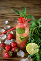 Lemonade with strawberry, lime, ice cubes and mint in a glass bottle