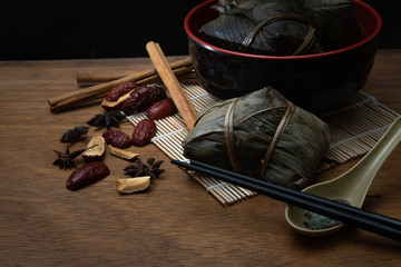 Zongzi or Traditional Chinese Rice Dumplings in a Bamboo leaf on a Wooden Table for Dragon Boat...