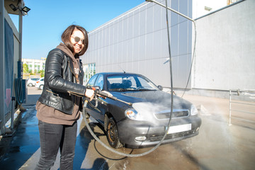 Fototapeta na wymiar young woman washing car at self-service carwash