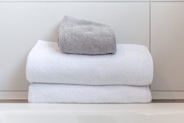 Fototapeta na wymiar White and gray folded towels against white tiles in bathroom