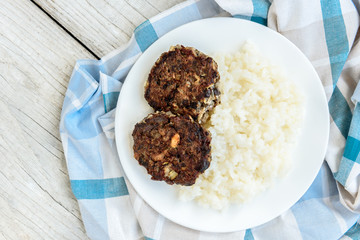 Homemade mushroom cutlets with rice porridge on wooden background. Healthy food for lunch or dinner.