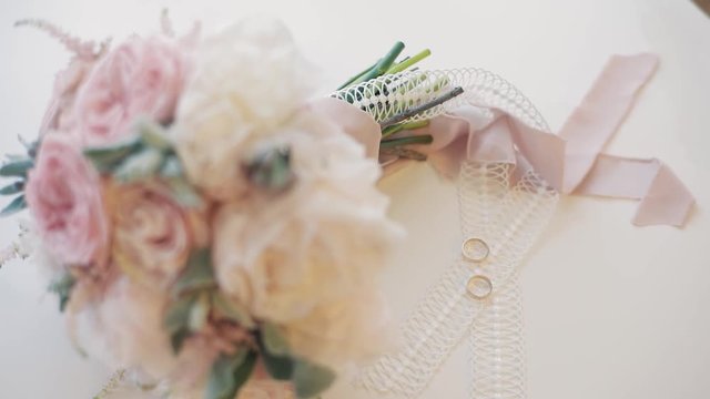 Wedding rings lie near beautiful wedding bouquet on the white floor