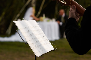 Cropped image of a musician and a rack with notes against a pair of newlyweds.