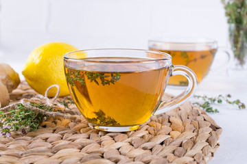 Glass cup of hot aromatic herbal tea with bunch of fresh wild thyme. Herbal drink.