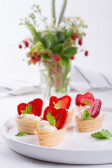 Mini tartlets on the plate . Homemade dessert with delicious cream cheese and fresh berries