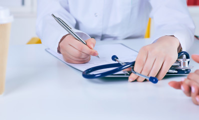 Close up of a female doctor filling up an application form while consulting patient. Medicine and health care concept