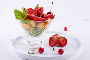 Fresh tasty mix fruit salad in the glass bowl on white table background. Healthy vitamin  breakfast