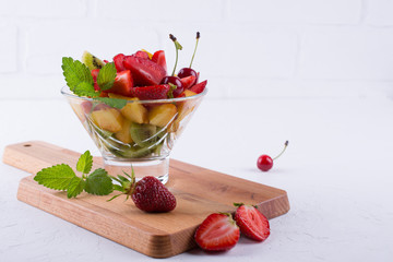Fresh tasty mix fruit salad in the glass bowl on white table background. Healthy vitamin  breakfast
