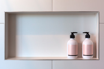 Relationship concept - two shampoo dispencers facing each other in white tiles shower niche with...