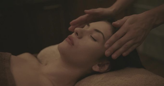 Young woman relaxing with reiki treatment at healtcare spa