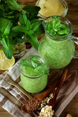 Green smoothie in a glass jar and jug topped with mint
