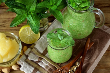 Green smoothie in a glass jar and jug topped with mint