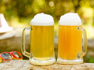 two beer in mug on green outdoor background