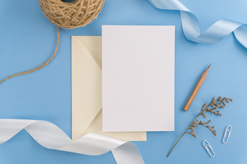 A wedding mock up concept. Wedding Invitation, envelopes, cards Papers on light blue background with ribbon and decoration. Top view, flat lay, copy space
