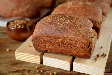 Loaves of rye bread sprinkled with coriander on a wooden board