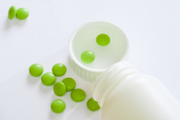 tablets medicine lying beside of plastic bottle. Pills and bottles are white. Isolated on white