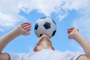 Teenage boy with a soccer ball on a of blue sky