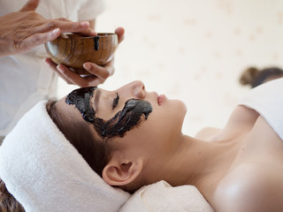 Spa concept. Young Asian woman with nutrient facial mask in beauty salon, close up