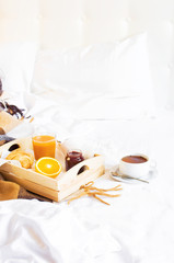 Breakfast Bed Cup of tea Croissant Orange juice Fresh orange Jam Wooden tray Bed linen Plaid in a...