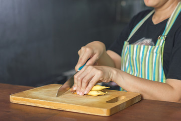 Close up on cook women hand cutting the Vegetable with a knife on wooden chopping block.