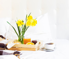 Breakfast Bed Cup of tea Croissant Orange juice Fresh orange Jam Wooden tray Bed linen Plaid in a cage Morning breakfast at the hotel Interior concept Top view Copy Space