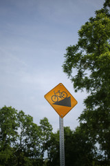 Yellow Downhill Bicycle Street Sign Isolated with Trees