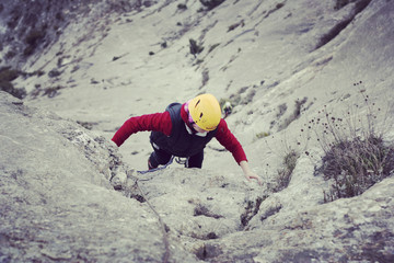 Woman rock climber. Rock climber climbs on a rocky wall. Woman makes hard move.