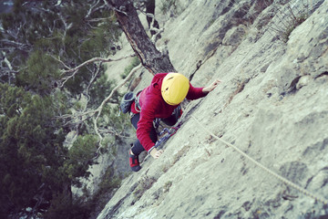 Woman rock climber. Rock climber climbs on a rocky wall. Woman makes hard move.