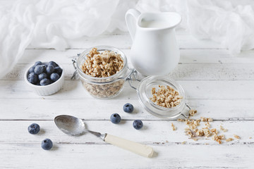 Oat flakes and fresh blueberries with milk. Delicious, healthy and useful breakfast on white wooden table background. Top view, close up.
