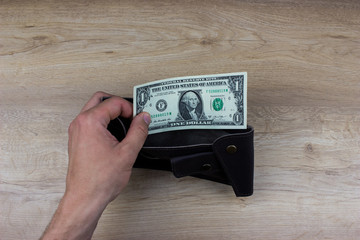 Mens hand holding one dollar banknote.  Empty wallet. Poverty concept