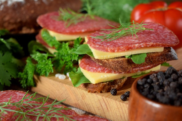 Sandwiches with salami, cheese and arugula salad surrounded by the ingredients