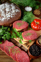 Sandwiches with salami, cheese and arugula salad surrounded by the ingredients
