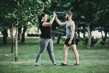 Gordijnen Plus size woman shaking arm of personal trainer © Vadym