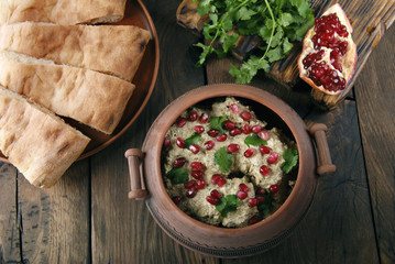 Satsivi with pomegranate seeds and cilantro is traditional georgian food. The Georgian dishes on a wooden background