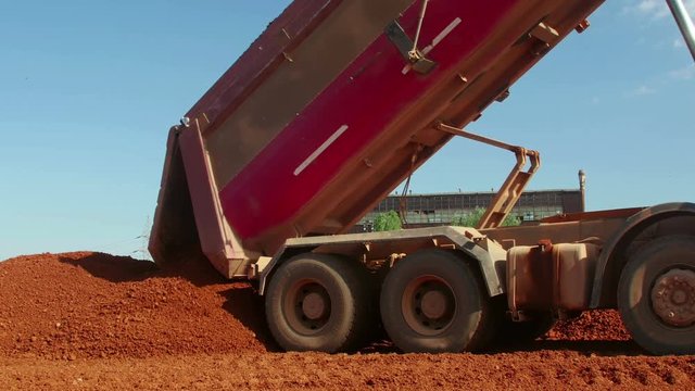 Dumper truck unloading ore for manufacturing plant