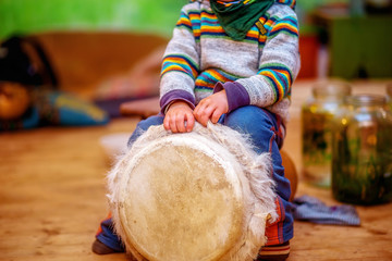 child playing a djembe drum with natural goat fur features.