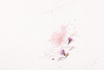 Scattered pink salt with flowers on white.