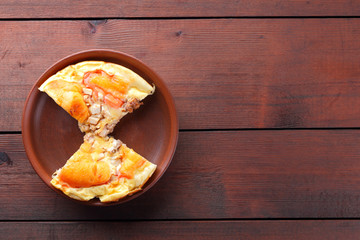 Homemade pizza on a clay plate, chopped pizza on a wooden background in rustic style, sandwiches with meat and cheese top view, delicious fast food in earthenware, American cuisine, copy space