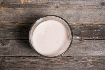 Cocoa drink in glass cup on wooden table. Tasty sweet drink for children